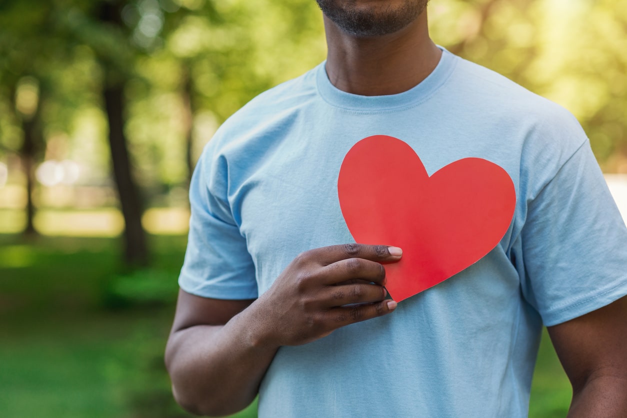 Image of a single adult male holding a red heart cutout over his chest