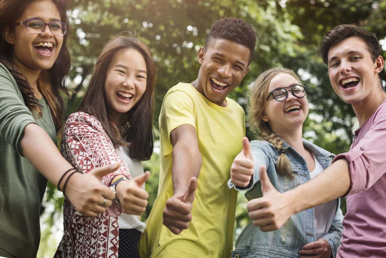 Image of diverse group of teens looking excited and giving thumbs up